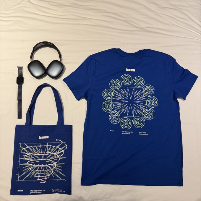 Flat lay of navy blue merchandise including a t-shirt and headphones with 'WEAVE' logo, alongside a tote bag featuring blockchain diagram designs and text reading 'a base The blockchain for global finance Token2049 Singapore 2026'.