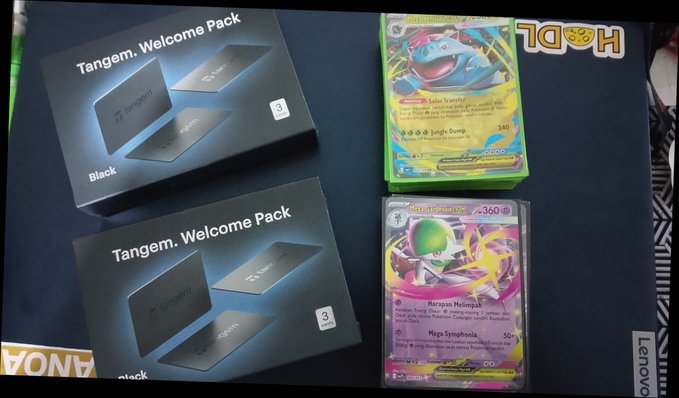 Two Tangem Welcome Pack boxes (Black edition) displayed next to Pokémon trading cards, including a Solar Tsuneki card and a Morganna Houpse card from the Surging Sparks set.
