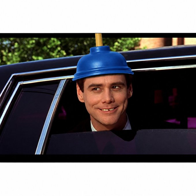 Jim Carrey from the movie "Dumb and Dumber" smiling from inside a car with a blue plunger suctioned onto his head.