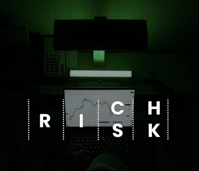A dark, moody image of a laptop displaying a stock chart with the word 'RISK' spelled out in white letters across the screen in a green-lit room.