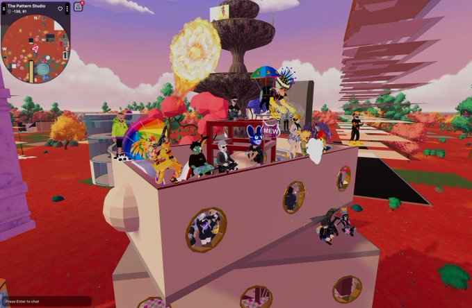 A colorful virtual 3D scene from 'The Pattern Studio' showing various cartoon avatars gathered on and around a pink building structure in a surreal landscape with explosions and a mini-map.
