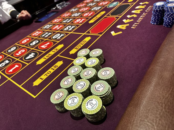 A roulette table at Caesars Atlantic City with stacks of green Roman Empire $1 chips on the betting layout and blue chips visible at the corner.