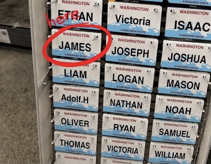 A souvenir display of Washington 'Evergreen State' license plate-style name tags, with 'here' written and a red circle highlighting the name 'JAMES'.