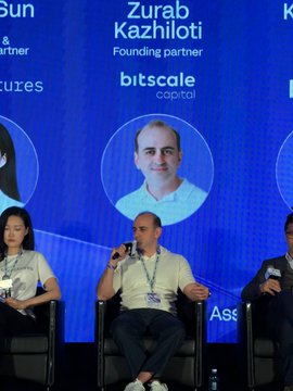 A photograph of a panel discussion featuring speakers identified on the blue backdrop as 'Zurab Kazhiloti, Founding partner' and 'bitscale capital'.