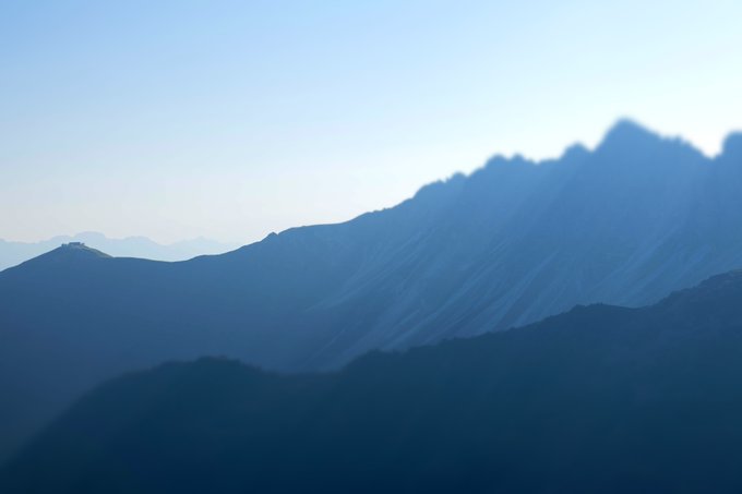 A hazy mountain landscape silhouetted in blue tones at dusk or dawn.