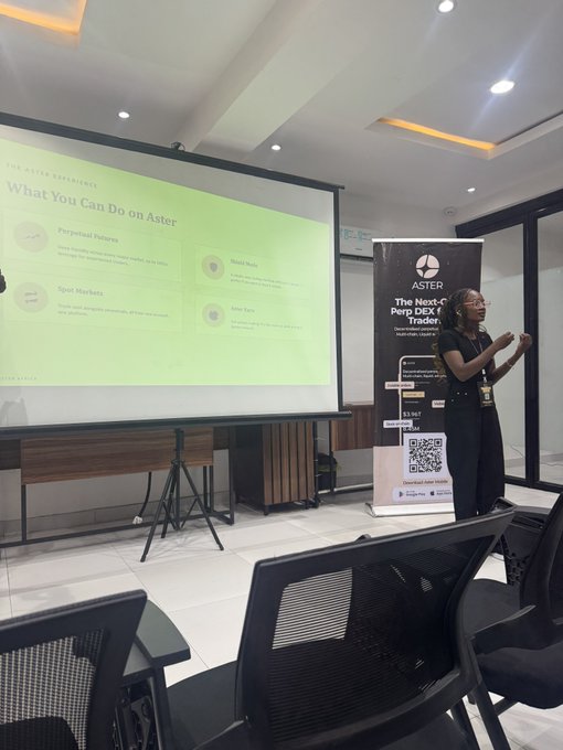 A woman presents at the Aster Dex Africa meetup in Lagos, standing beside an Aster banner reading "The Next-Gen Perp DEX Trader" with a QR code, while a projected slide titled "What You Can Do on Aster" highlights features like Perpetual Futures, Spot Markets, Model Mode, and Aster Earn.