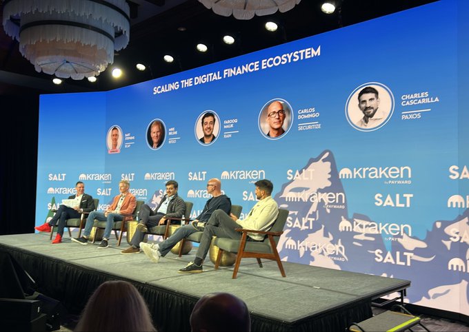 A panel discussion titled 'SCALING THE DIGITAL FINANCE ECOSYSTEM' at a Kraken and SALT event, featuring speakers including Charles Cascarilla (Paxos) and Carlos Domingo (Securitize) seated on stage.