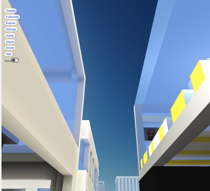 A screenshot from a virtual 3D environment with blocky buildings against a blue sky, featuring a menu with options like 'Theatre', 'Fullscreen', 'Explore', 'Settings', 'Avatar', 'Dance', 'Emote', 'Yeet', and a 'Voice' toggle.
