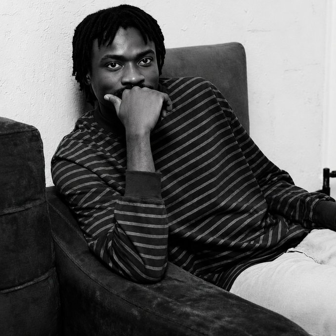 A black-and-white photo shows a young man with locs wearing a striped sweater, seated and resting his fist against his mouth in a thoughtful, contemplative pose that mirrors the post's confusion about web3 migration.