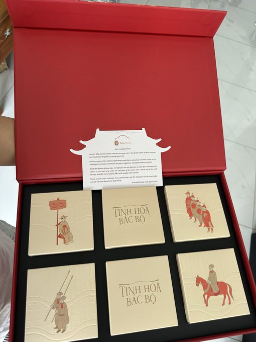 An open red gift box containing six decorative tiles with Vietnamese cultural figures and the text 'TINH HOA BẮC BỘ', along with a small informational card.