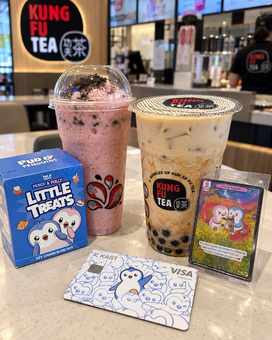 Two Kung Fu Tea bubble drinks sit on a counter alongside a 'Little Treats' Penchi & Polly blind box, a Pokemon-themed card, and a Visa prepaid card.