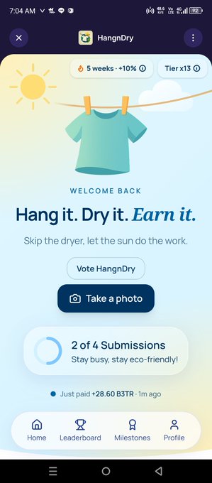 A mobile app screenshot for 'HangnDry' displaying a teal t-shirt hanging on a clothesline, with the tagline 'Hang it. Dry it. Earn it.' and options to 'Vote HangnDry' and 'Take a photo.'