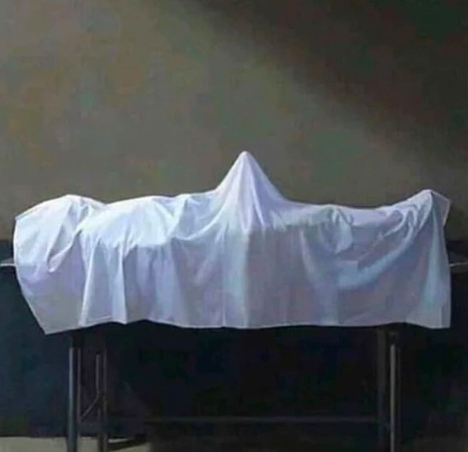 A large white cloth drapes over an unseen object on a table, concealing whatever is beneath—evoking a classic "unveiling" moment. The shrouded form visually represents the anticipation of finally revealing $ASTER, as suggested by the accompanying caption.