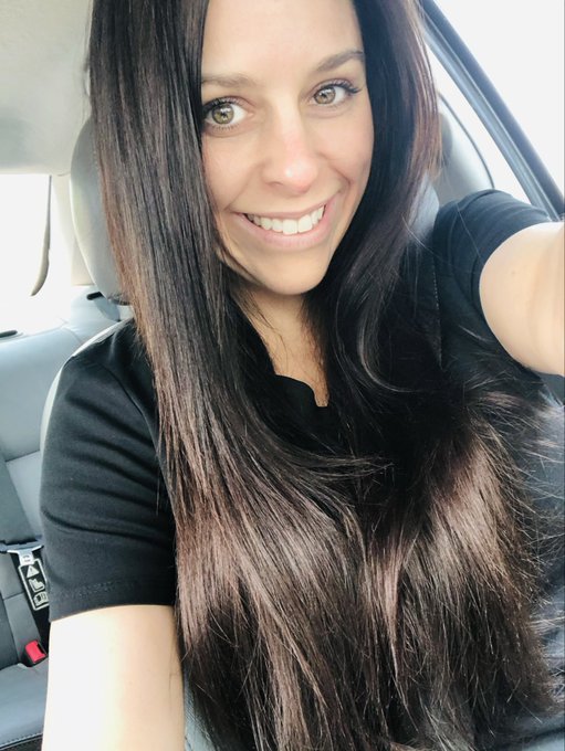 A woman with long dark hair smiles in a selfie taken inside a car, wearing the black top she humorously references in her post about buying a HEX investment with her 401k back in 2021.