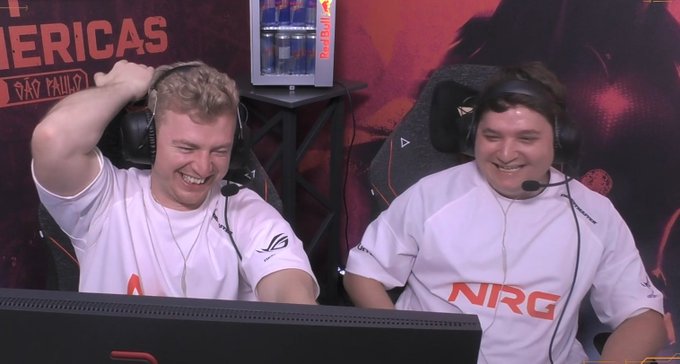 Two esports players wearing white jerseys—one displaying the "NRG" logo—sit laughing in front of a Red Bull-branded backdrop with "São Paulo" and "Americas" text visible, suggesting a joyful, lighthearted moment during a tournament.