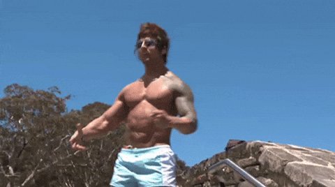 The image features a muscular man with a tattooed arm standing against a blue sky background. He appears to be posing for a photo or video while wearing shorts, which suggests that he might be at an outdoor location such as a beach or poolside. The caption of the image reads "I’m down a lot, but still holding," implying that despite his physical exertion, he is still able to maintain some level of control over the situation. This could be related to the post's theme of summer, which might suggest an active lifestyle and outdoor activities during warmer months.