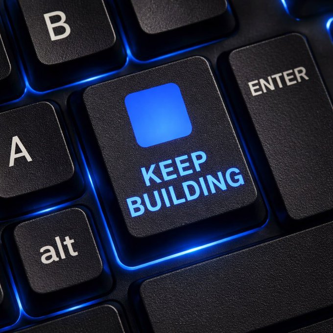 A close-up photo of a black backlit computer keyboard featuring a prominent key labeled "KEEP BUILDING" with a blue square icon, surrounded by keys labeled "A," "B," "alt," and "ENTER."