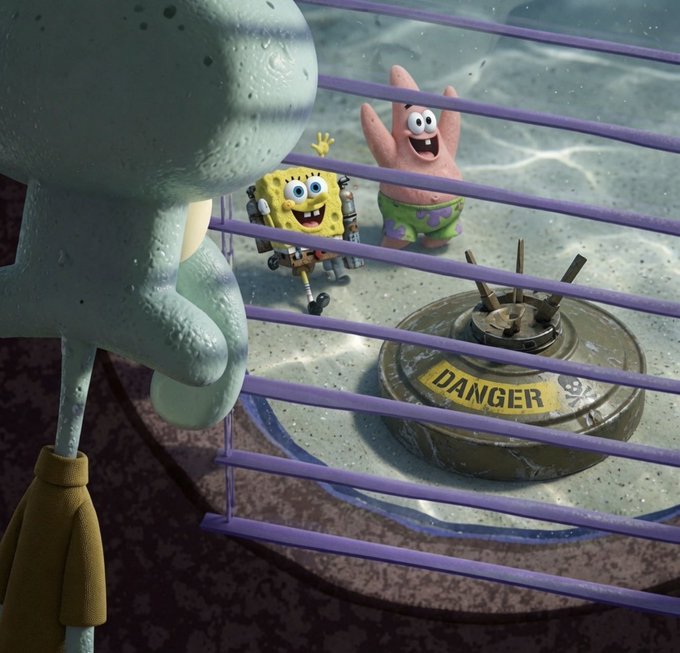 A scene from SpongeBob SquarePants shows Squidward looking at SpongeBob and Patrick, who are staring through the bars of a cage at a landmine labeled 'DANGER'.