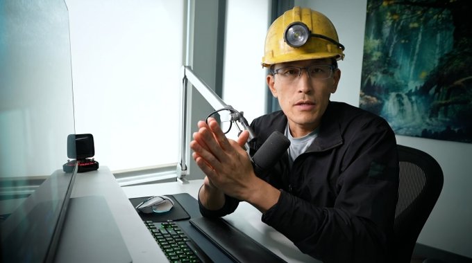 A man wearing a yellow hard hat with a headlamp and glasses sits at a computer desk with his hands clasped together. The post suggests the image is a thumbnail for a video where the creator explains their decision to sell all their Bitcoin to mine ORE tokens.