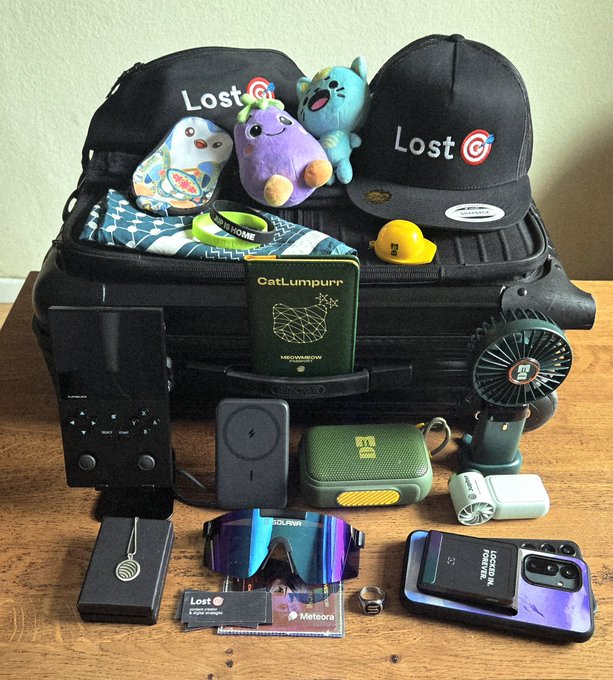 The image features an assortment of items laid out on top of a suitcase or luggage bag, including hats, sunglasses, books, and other miscellaneous objects. The scene appears to be related to a travel-related post by someone who has been following the person for some time. The hat in particular seems to have a humorous message written on it, which adds to the lighthearted nature of the post.