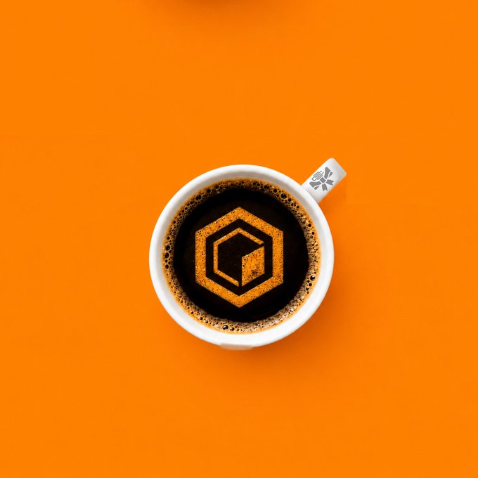 A top-down view of a white coffee cup on a bright orange background, with a hexagonal logo design visible in the dark coffee foam.