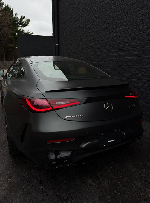A matte black Mercedes-AMG CLS 63 parked next to a dark brick wall.