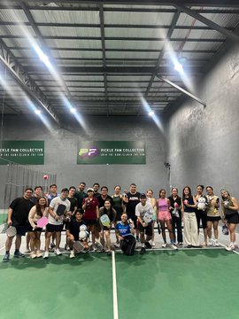 A large group of people posing together for a photo inside an indoor pickleball facility, with banners reading "EP PICKLE PAW COLLECTIVE."