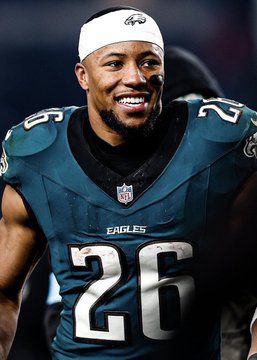 Philadelphia Eagles running back Saquon Barkley (#26) smiles on the field in his midnight green jersey, representing the team that a bettor is backing to cover the spread with a $132k wager on Polymarket.