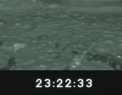 A grainy, night-vision style image with a timestamp of '23:22:33' showing a dark, indistinct scene that resembles a wooded or outdoor area.