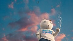 An animated or rendered image of a small white cat-like character wearing a shirt, standing against a backdrop of blue sky with pink clouds.