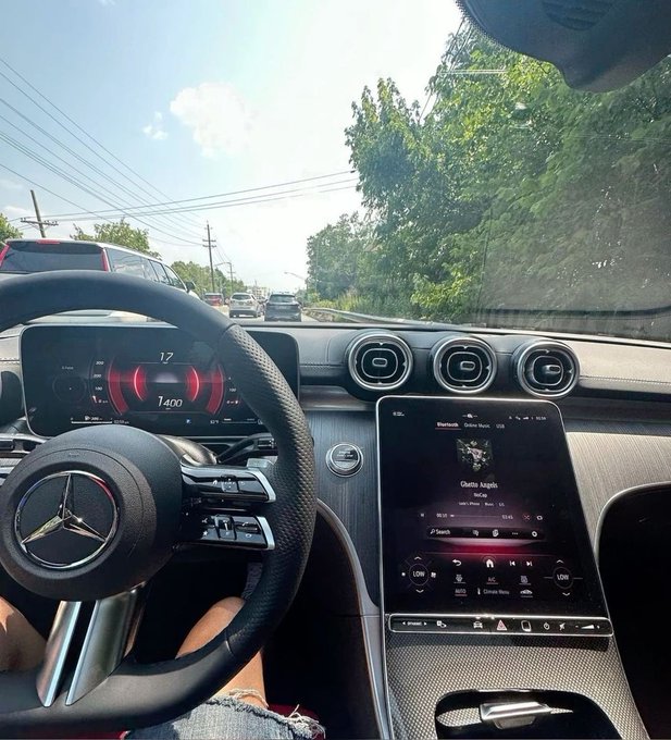 A driver enjoys a Friday commute from the perspective of a Mercedes-Benz, with the digital dashboard showing a speed of 17 mph at 1400 RPM and the infotainment screen playing "Gotta Laugh" by Sean Paul on Bluetooth audio.