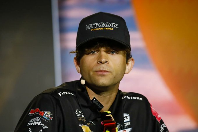 The image features a man wearing a black baseball cap with the word "BTCOM" written on it, sitting down and looking at the camera. The caption below his photo reads "LATEST: Jack Mallers just said 'No man work for what another man can print'. Focus on what is in the image and how it relates to the post." This suggests that the man's statement may be related to a recent event or conversation involving the use of printing technology, possibly in the context of sports.