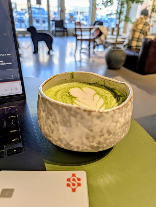 The image features a laptop computer sitting on top of a table next to a bowl filled with green tea. The laptop screen displays an advertisement for a digital currency called Dash, which allows users to buy things instantly using their digital wallet. This suggests that the person who set up this scene might be interested in exploring new ways to manage their finances or engage in online shopping experiences.