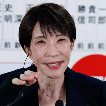 The image shows a Japanese woman speaking at a press conference, with Japanese text visible in the background, likely related to the post's message of "GO SBI JAPAN.. GO XRP..".