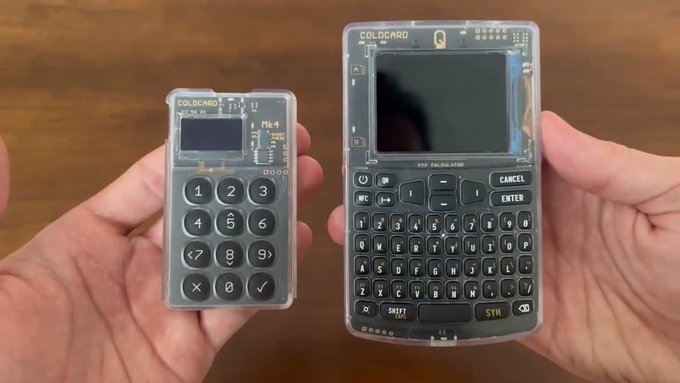 Two hands holding up transparent, DIY handheld computing devices labeled 'COLDCARD' — a smaller numeric keypad model on the left and a larger QWERTY-keyboard model on the right.