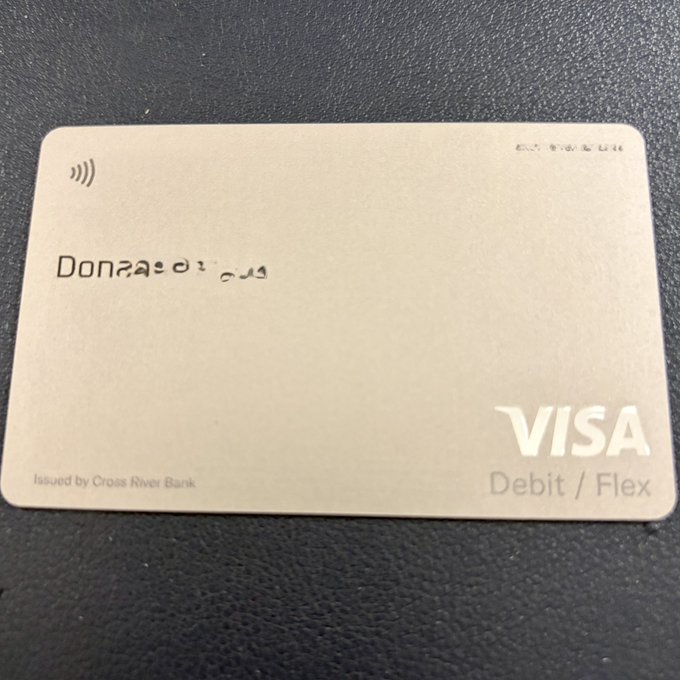 A metallic X Money Visa Debit/Flex card issued by Cross River Bank, personalized with the name "Donovan" and a contactless symbol, resting on a dark surface. The image illustrates the post's argument about the seamless integration of 𝕏 Money within the X platform rather than as a separate app.