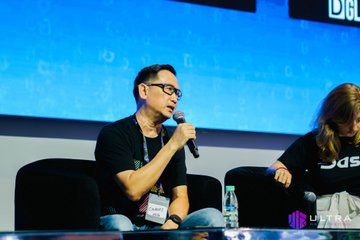 A man with glasses speaks into a microphone while moderating a panel at Ultra Web3 Fest, with a woman seated beside him on stage. The event's branding is visible in the background, and the "ULTRA" logo appears in the corner, matching the post about hosting the panel.