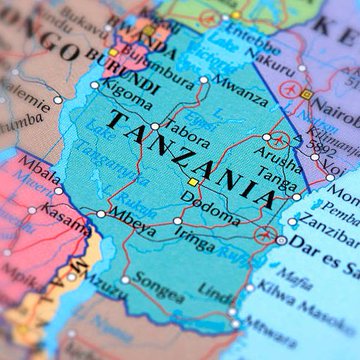 The image shows a close-up of a colorful map highlighting Tanzania, with visible text including "TANZANIA," "Dodoma" (the capital), and "Dar es Salaam," along with surrounding regions like Kenya, Burundi, and the Indian Ocean. This map visually contextualizes the news of Tanzania preparing new cryptocurrency regulations, aligning with similar moves by neighboring Kenya and Zimbabwe amid Africa's growing crypto market.
