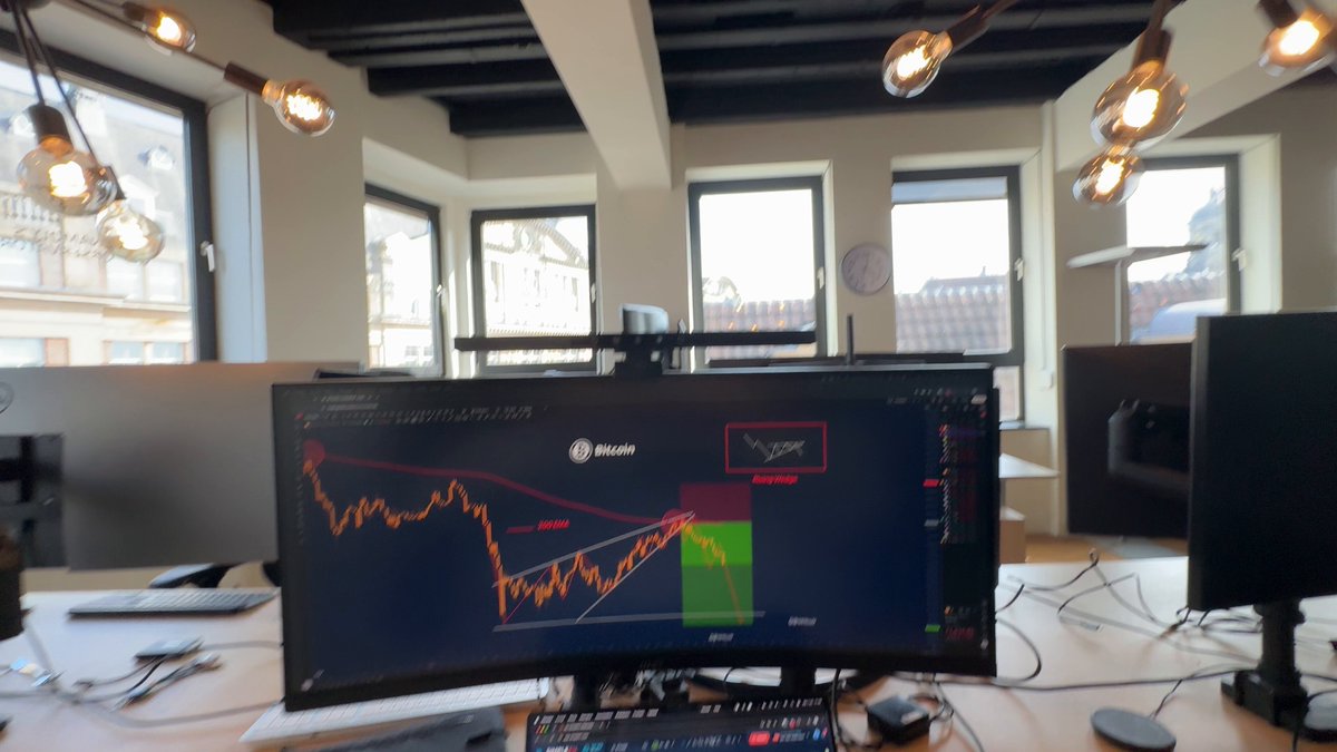 The image shows a computer monitor displaying a stock chart, with Bitcoin's price dropping rapidly. The text in the image suggests that there might be panic among investors due to the falling prices of Bitcoin. However, one person seems to be enjoying this situation as they are actively trading Bitcoin and making a profit from it.