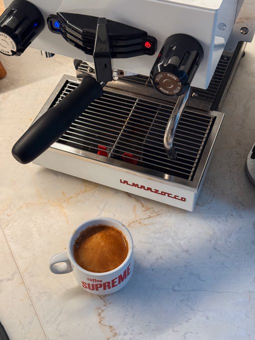 A morning espresso from a La Marzocco machine pairs with a "Supreme Coffee" branded cup, capturing the quintessential "Gm" (good morning) ritual.