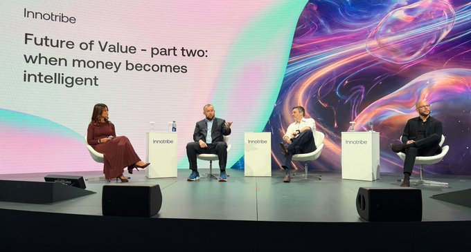 Four panelists sit in white chairs on a stage at an 'Innotribe' event, with a large screen behind them displaying the title 'Future of Value - part two: when money becomes intelligent'.