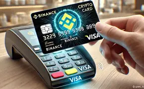 A hand holding a Binance-branded Visa crypto card over a payment terminal, showing a glowing Binance logo with 'CRYPTO CARD' text.