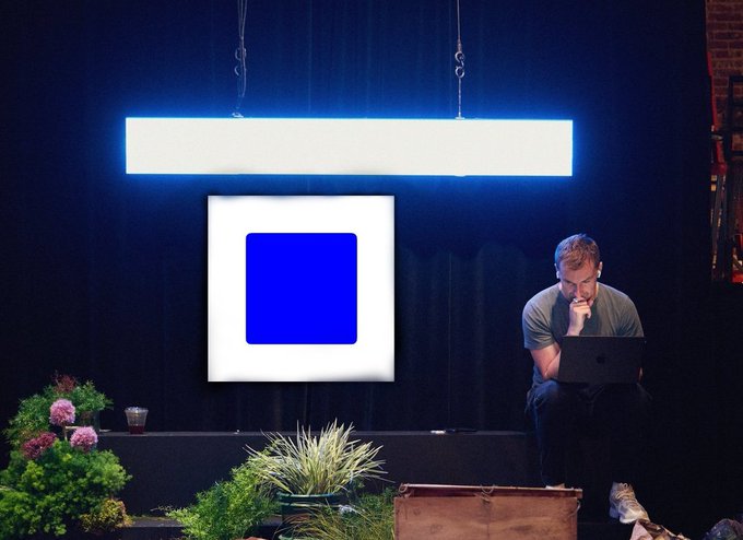 The image shows a man sitting at a computer, using an app that has been described as a game changer for beginners due to its smooth onboarding process and user-friendly interface. The man appears to be focused on his work or task at hand while seated in front of a large screen with a blue square displayed prominently above him.