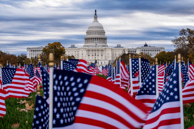 The U.S. Capitol building stands prominently in the background beneath a cloudy sky, framed by a field of small American flags planted in the grass, symbolizing American legislative governance. The image visually reinforces the post about the Senate's forthcoming Sept. 15 procedural vote on the CLARITY Act, which seeks to establish a regulatory framework for digital assets in the United States.