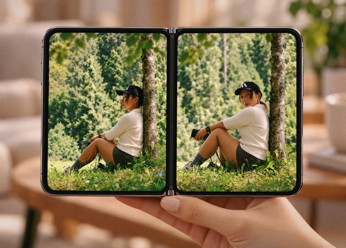 A person holds an unfolded dual-screen device displaying two photos of a woman in a white top and black shorts sitting against a tree in a forest, creatively showcasing the "duo" concept referenced by the $MPLX ticker. The twin screens side-by-side mirror the dual nature implied by the caption.