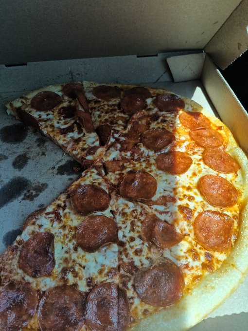 A pepperoni pizza in a cardboard box with one slice separated from the rest.