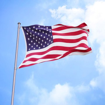 An American flag with stars and stripes waving on a flagpole against a backdrop of blue sky with scattered white clouds.