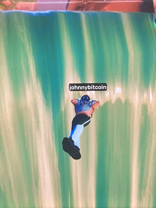 A person sliding face-down down a green slip-and-slide with the watermark 'johnnybitcoin' visible across the center.