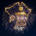 A nighttime aerial view of a large illuminated building complex with fireworks.
