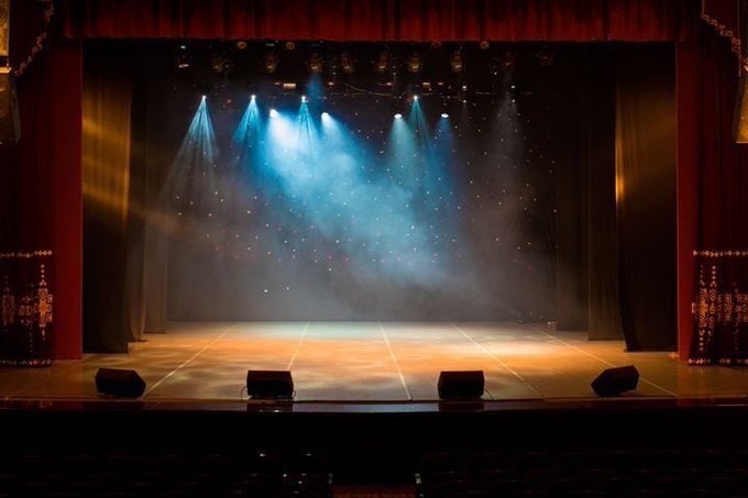 An empty theater stage illuminated by blue spotlights with no visible text or numbers, paired with a post about XRP's "RESET" reaching its final stage — suggesting the staged, dramatic visual symbolizes a climactic moment of transformation or anticipation in the cryptocurrency's trajectory.